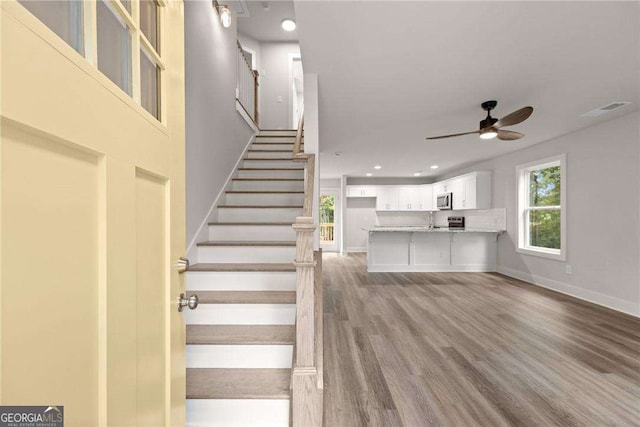 stairs featuring ceiling fan, hardwood / wood-style floors, and sink