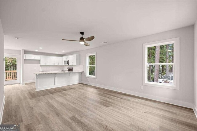 unfurnished living room featuring ceiling fan and light hardwood / wood-style flooring