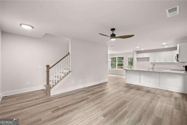 unfurnished living room with ceiling fan, sink, and light hardwood / wood-style flooring