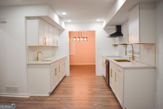 kitchen with white cabinets, wall chimney exhaust hood, black electric cooktop, and sink