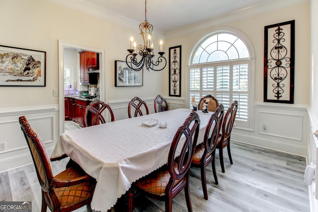 dining space featuring a notable chandelier, ornamental molding, and light hardwood / wood-style flooring