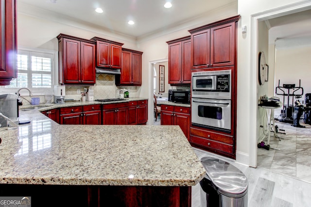 kitchen featuring a kitchen breakfast bar, light stone counters, tasteful backsplash, and appliances with stainless steel finishes