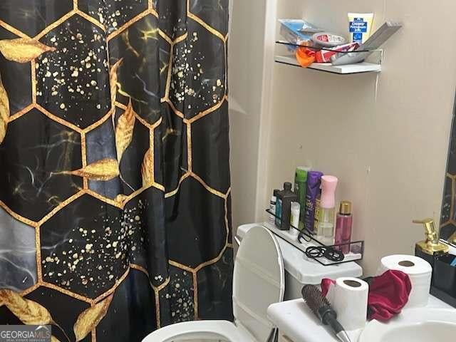 bathroom featuring curtained shower and toilet