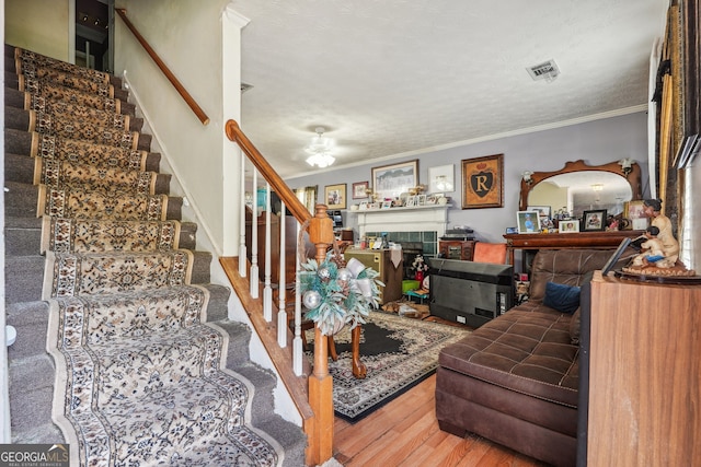 living room with hardwood / wood-style flooring, ornamental molding, a fireplace, and a textured ceiling