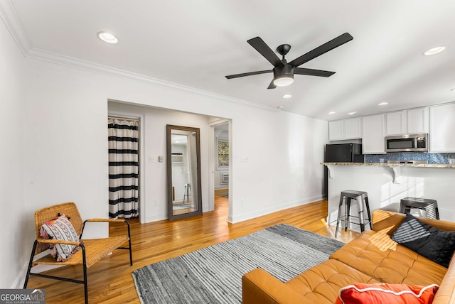 living room with ceiling fan, crown molding, and light hardwood / wood-style floors