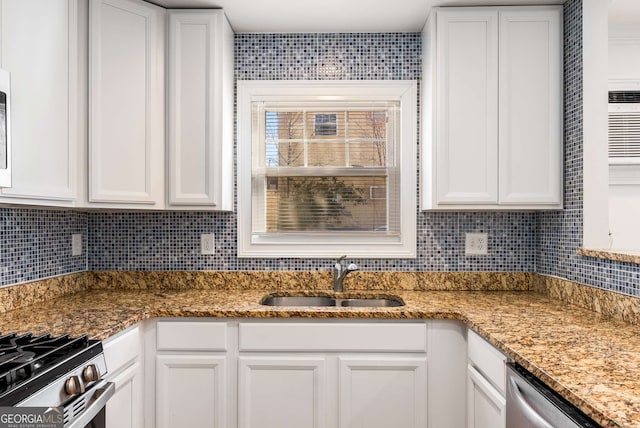 kitchen featuring appliances with stainless steel finishes, sink, stone countertops, and white cabinetry