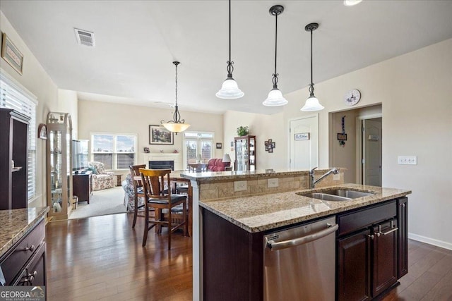 kitchen featuring dishwasher, a center island with sink, sink, decorative light fixtures, and dark brown cabinets