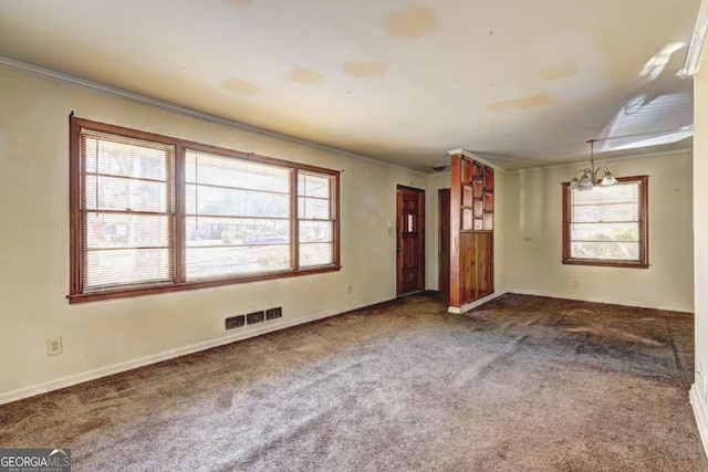 carpeted spare room featuring ornamental molding and an inviting chandelier