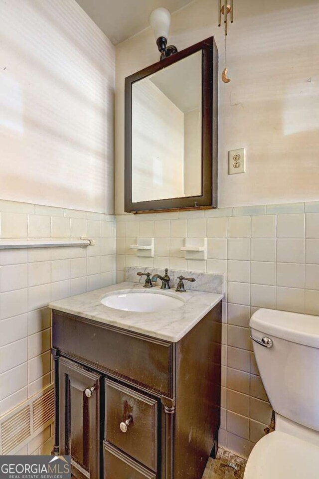 bathroom with vanity, toilet, and tile walls