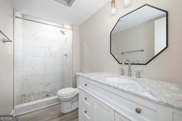 bathroom with tiled shower, hardwood / wood-style flooring, vanity, and toilet