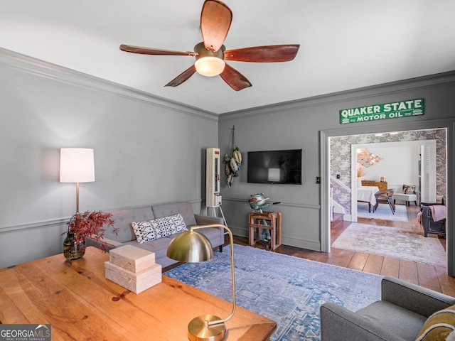 living room with ceiling fan, wood-type flooring, and ornamental molding