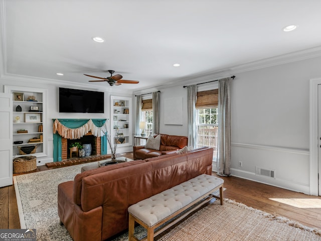 living room featuring hardwood / wood-style floors, built in features, and crown molding