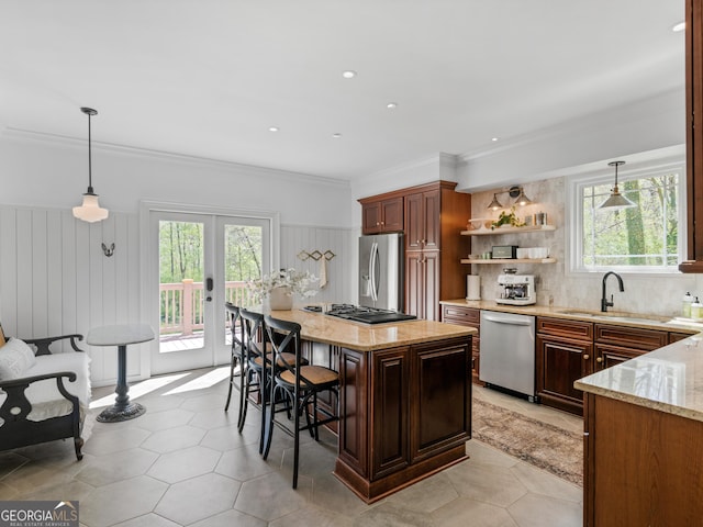 kitchen featuring a kitchen bar, french doors, stainless steel appliances, sink, and decorative light fixtures