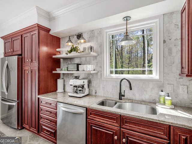 kitchen featuring hanging light fixtures, sink, appliances with stainless steel finishes, plenty of natural light, and light stone counters