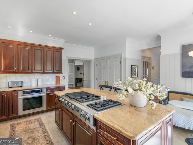 kitchen with light stone countertops, stainless steel appliances, backsplash, crown molding, and a kitchen island