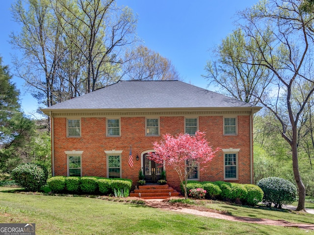 colonial-style house featuring french doors and a front lawn