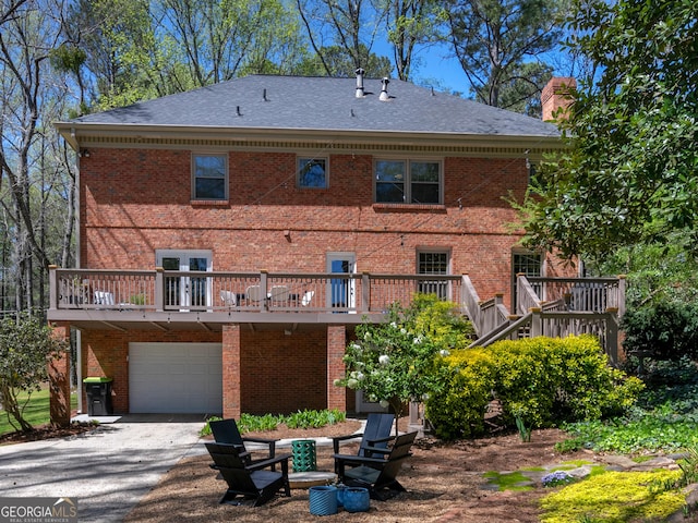 rear view of property featuring a garage and a wooden deck