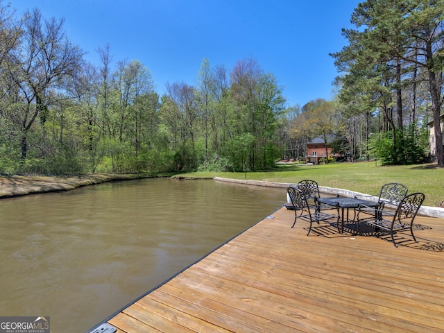 view of dock with a yard and a water view