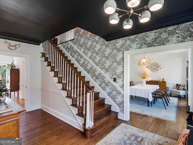 staircase with a chandelier, crown molding, and wood-type flooring