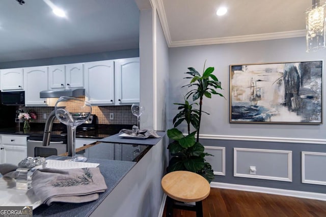 kitchen featuring dark wood-type flooring, backsplash, crown molding, stainless steel electric stove, and white cabinets