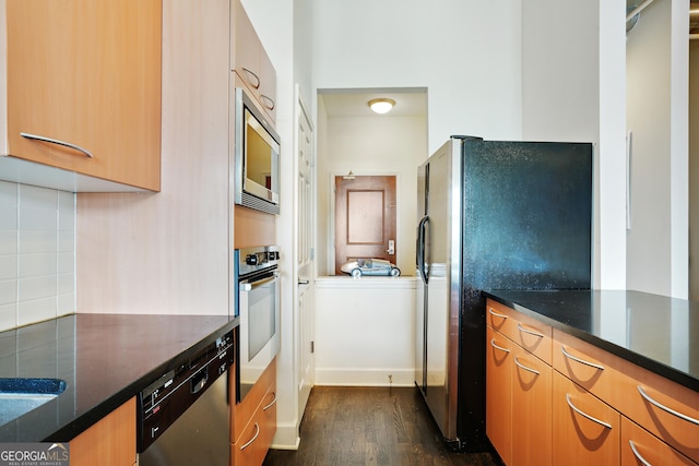 kitchen featuring dark stone counters, decorative backsplash, dark hardwood / wood-style flooring, and stainless steel appliances