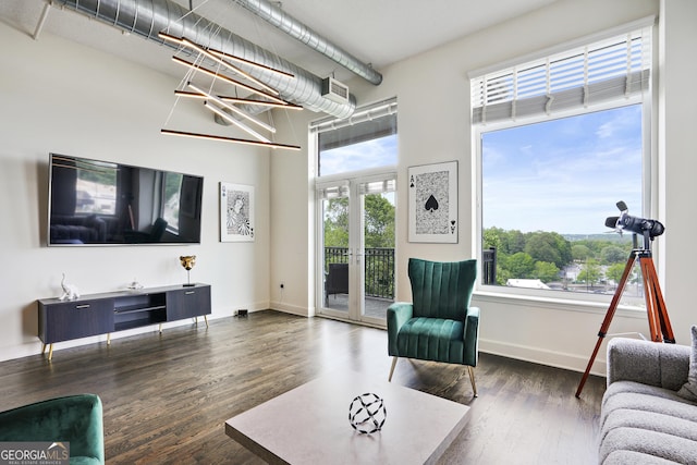 living room with a chandelier, french doors, a towering ceiling, and dark wood-type flooring