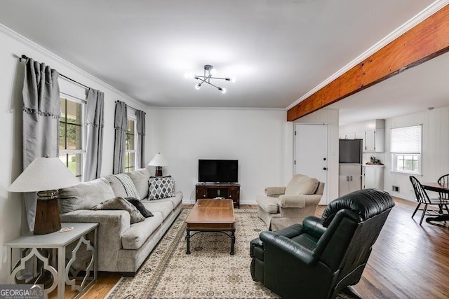 living room with light hardwood / wood-style flooring, ornamental molding, and a notable chandelier