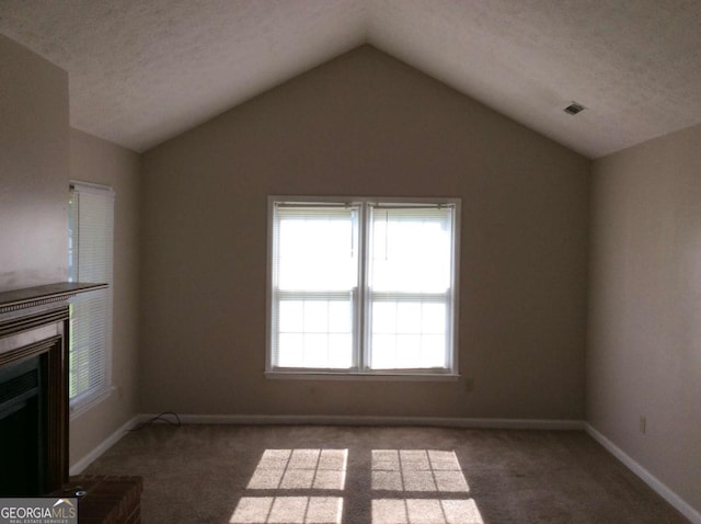 unfurnished living room with dark colored carpet, a textured ceiling, and lofted ceiling