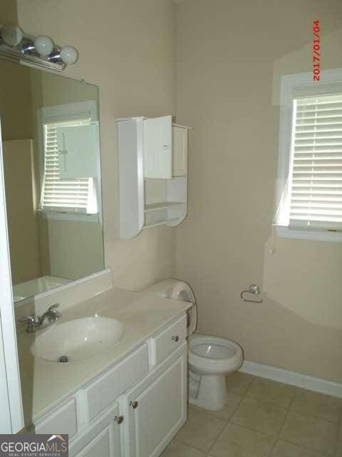 bathroom featuring toilet, vanity, and tile patterned floors