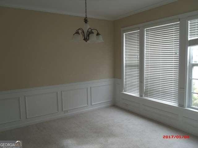 carpeted spare room featuring ornamental molding and an inviting chandelier