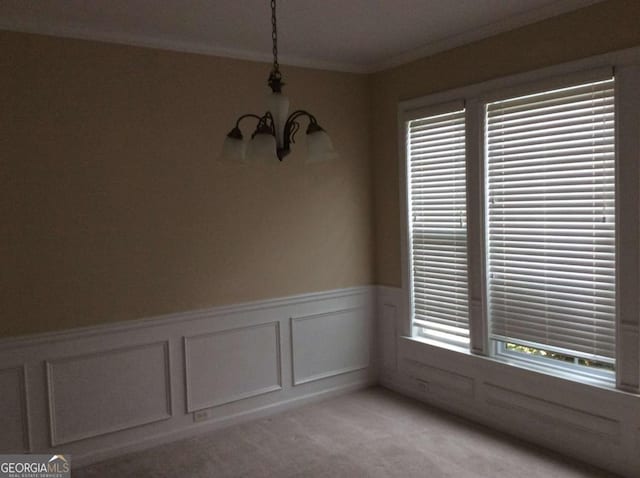 spare room featuring light carpet, an inviting chandelier, plenty of natural light, and ornamental molding