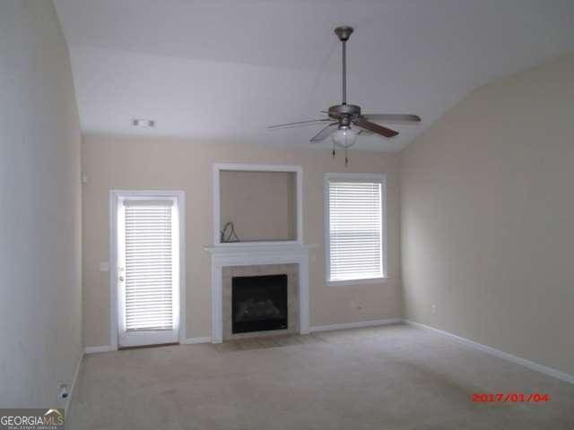 unfurnished living room with ceiling fan, plenty of natural light, light colored carpet, and lofted ceiling