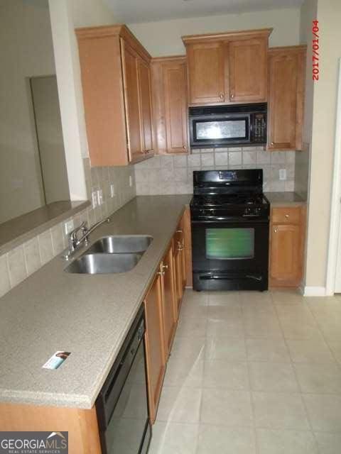 kitchen with tasteful backsplash, sink, and black appliances