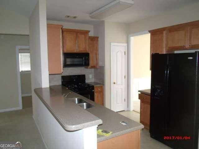 kitchen with black appliances, kitchen peninsula, sink, and tasteful backsplash