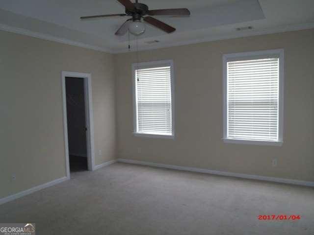 empty room with ceiling fan, crown molding, and carpet floors