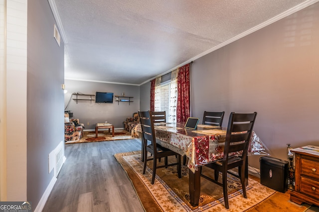 dining room featuring hardwood / wood-style floors, a textured ceiling, and crown molding