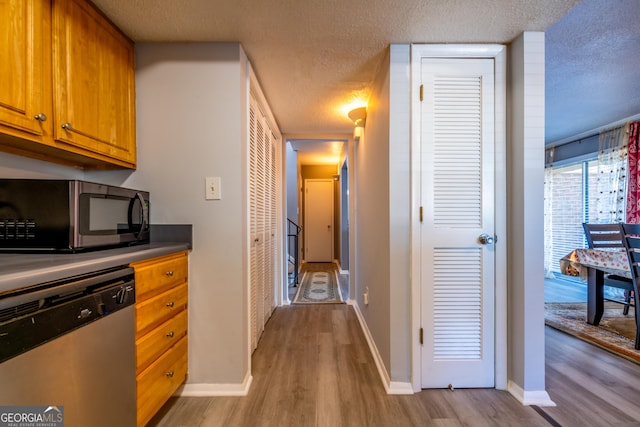 kitchen featuring dishwasher, light wood-type flooring, and a textured ceiling