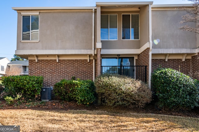 rear view of house featuring central AC unit and a lawn