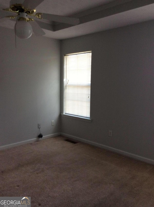 carpeted empty room with a raised ceiling and ceiling fan