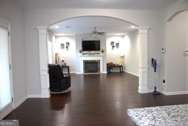 living room with decorative columns, ceiling fan, and dark wood-type flooring