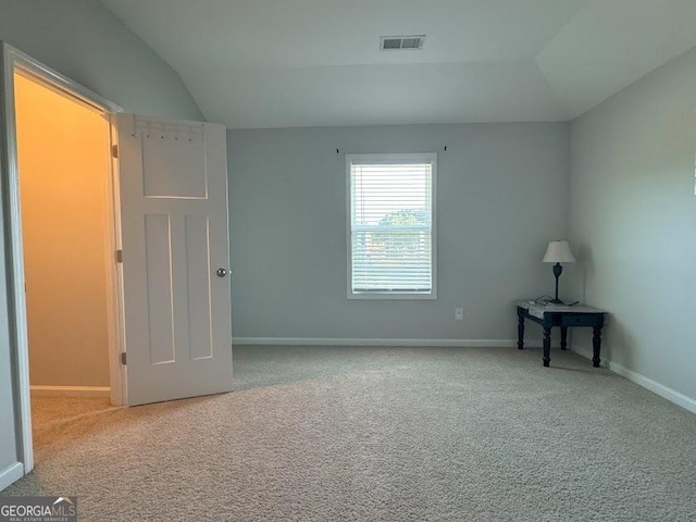 spare room with light colored carpet and vaulted ceiling