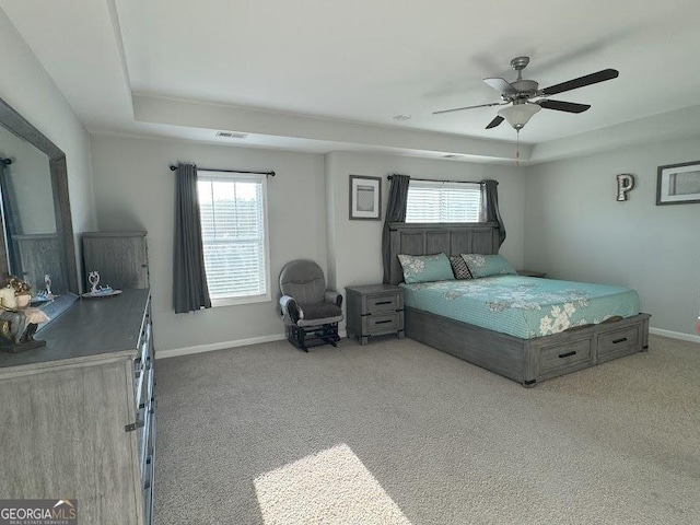 bedroom with carpet flooring, a tray ceiling, and ceiling fan