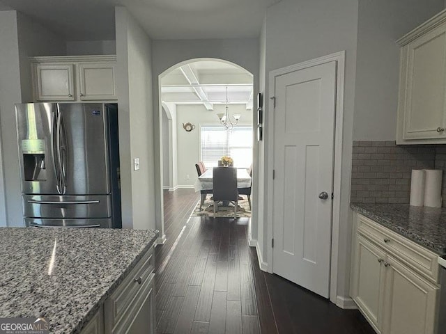 kitchen with beamed ceiling, stainless steel refrigerator with ice dispenser, light stone counters, and coffered ceiling