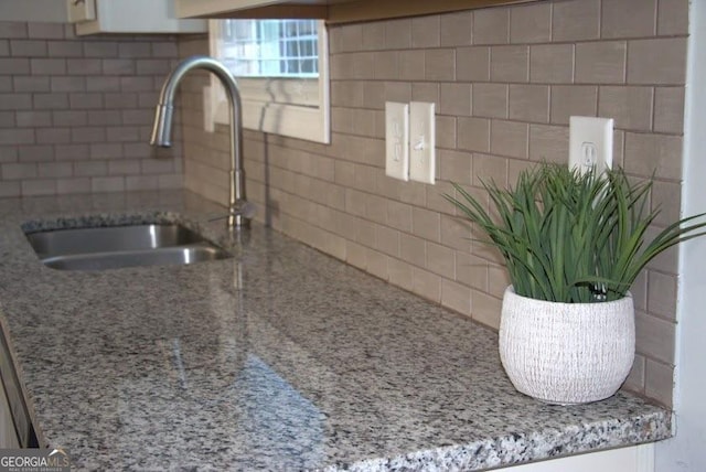 room details featuring light stone countertops, sink, and tasteful backsplash