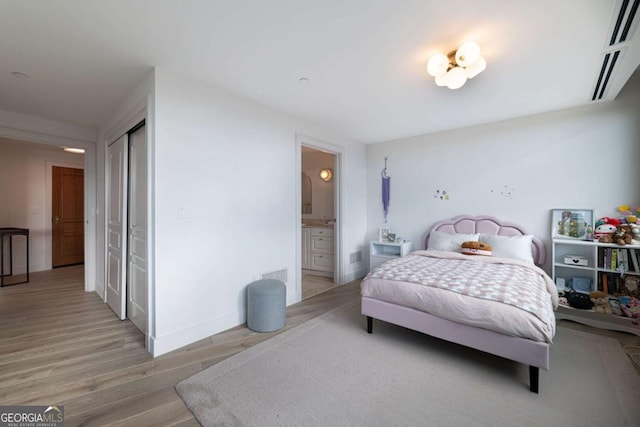 bedroom with hardwood / wood-style floors, a closet, and ensuite bath