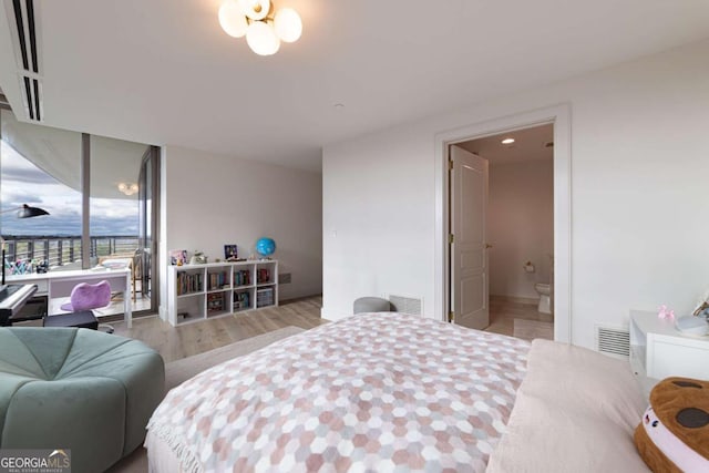 bedroom featuring connected bathroom and light hardwood / wood-style flooring