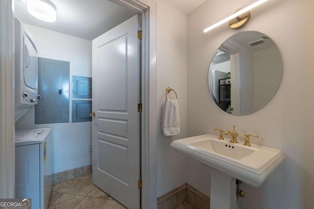 bathroom with tile patterned flooring, electric panel, stacked washer and dryer, and sink