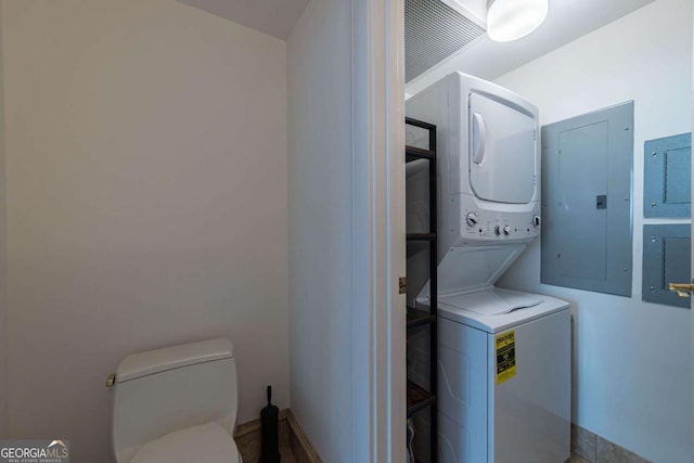 clothes washing area featuring stacked washer / dryer and electric panel