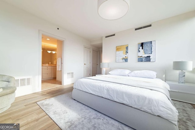 bedroom with wood-type flooring and connected bathroom