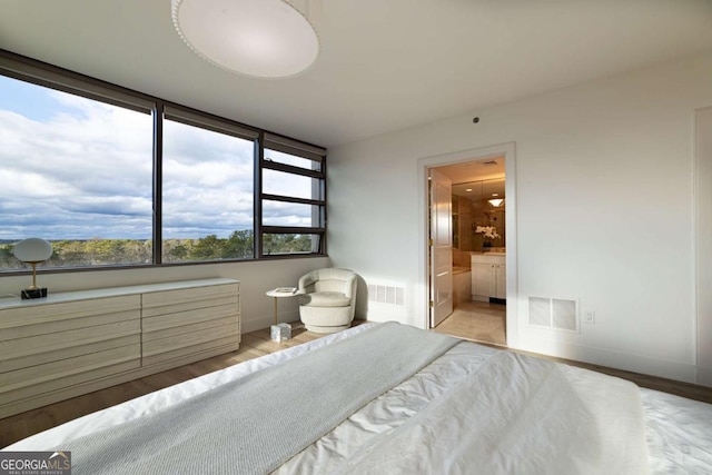 bedroom with light wood-type flooring and ensuite bath